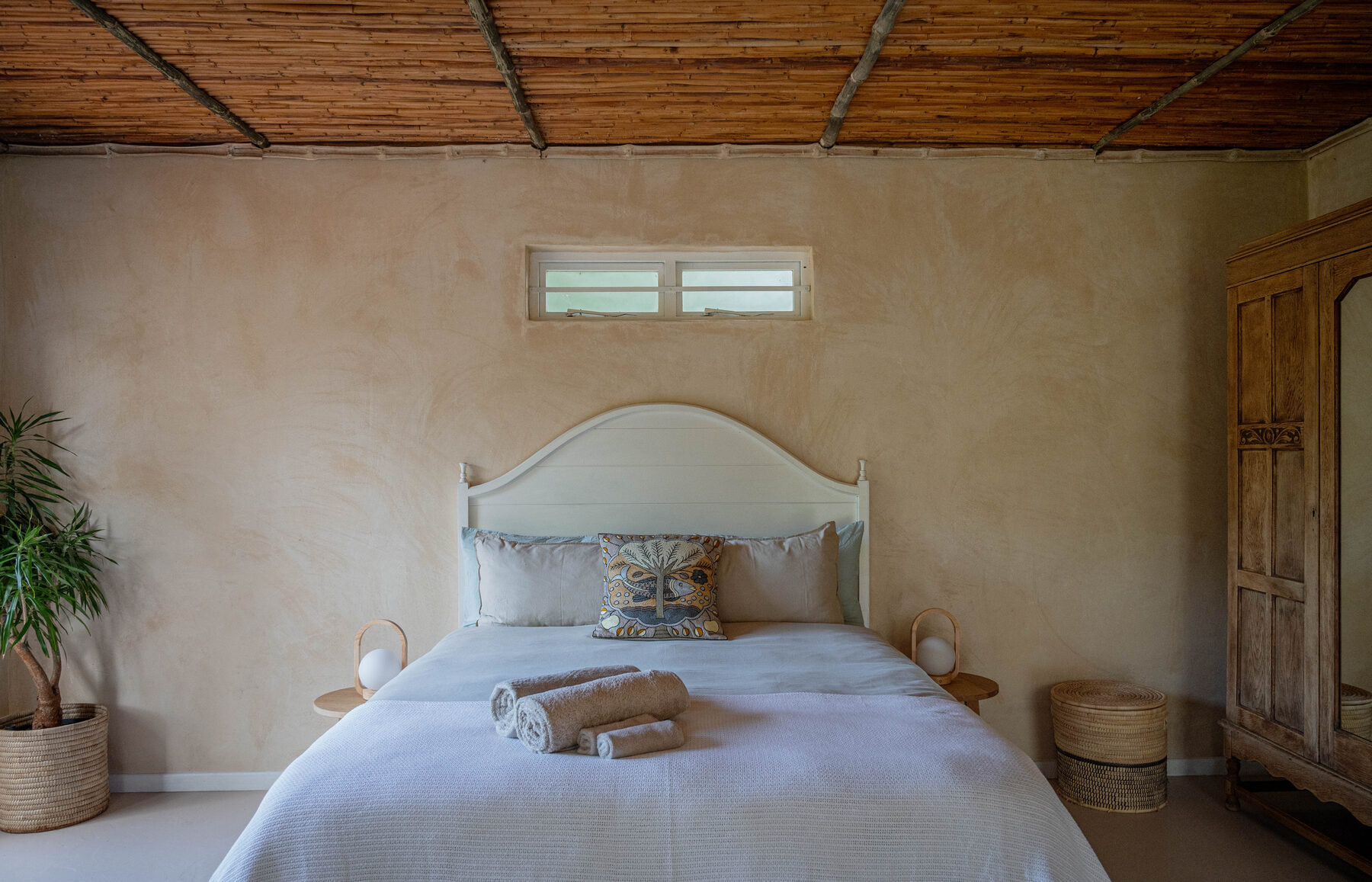 Bedroom under a bamboo ceiling, plaster walls, linen dressed